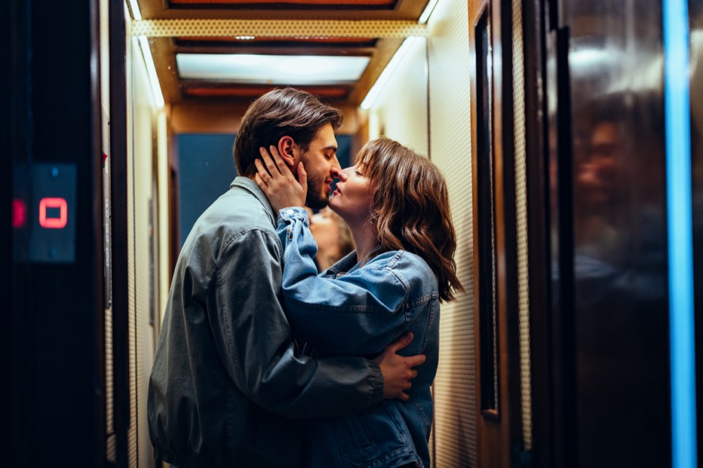 A happy couple laughing and kissing in an elevator